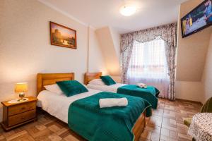 a hotel room with two beds and a television at Willa ROZA in Łeba