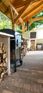 a barbecue under a wooden roof with a pile of wood at Megnyugtat-LAK Vendégház in Tokaj