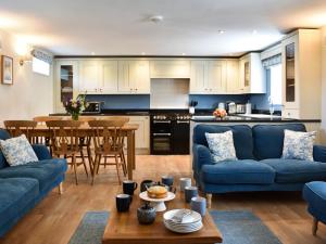 a living room with blue couches and a kitchen at The Old Workshop in Keswick