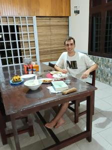 Un homme assis à une table avec de la nourriture sur elle dans l'établissement EL Homestay Bunaken, à Bunaken