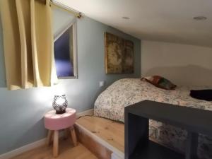 een kleine slaapkamer met een bed en een roze kruk bij Le Grain de Sable, studio avec mezzanine in Tonneins