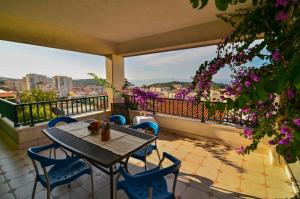 a table and chairs on a balcony with purple flowers at Apartments Mustapic in Makarska