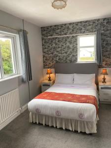 a bedroom with a large bed and two windows at Clonmore Lodge B&B in Quilty