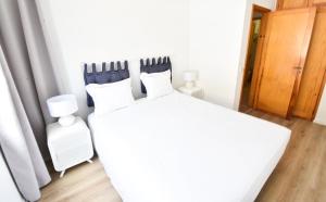 un letto bianco con quattro cuscini in una stanza di Beach house Quiaios I Figueira da Foz a Quiaios