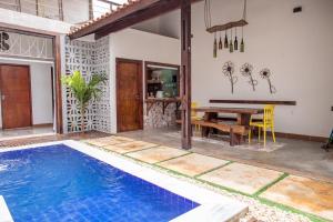 a villa with a swimming pool and a wooden table at Casa 3 amores PREÁ, vento, charme, piscina e 2 quartos in Prea