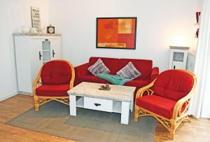 a living room with a red couch and two chairs at Ferienwohnung mit Balkon und Stran in Ostseebad Sellin