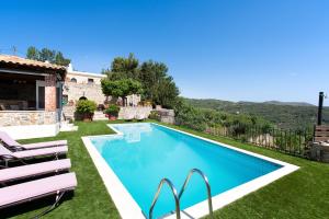 a swimming pool with lawn chairs and a house at Metohi Nature Living in Kastamonítsa