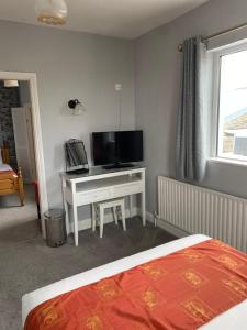 a bedroom with a bed and a desk with a television at Clonmore Lodge B&B in Quilty