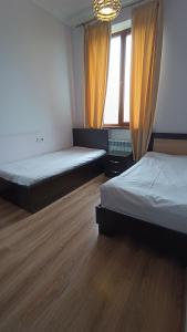 two beds in a room with wooden floors and windows at Elite Apartments in Yerevan