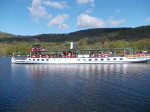 um grande barco na água com pessoas nele em Landing Cottage Guest House em Newby Bridge