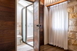 a bathroom with a glass door leading to a toilet at Via Maria Boutique Suites In The Middle Of The city in Haifa