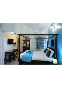 1 dormitorio con cama con dosel y escritorio en Le Clarisse Guest House, en Pondicherry