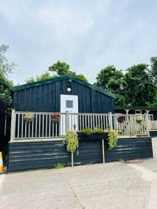 a black building with a white fence and potted plants at The Granary in Birchington