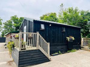 a black tiny house with a wooden staircase at The Granary in Birchington