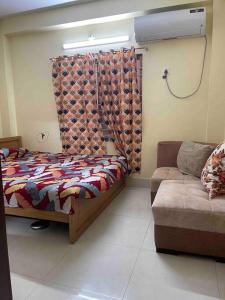 a bedroom with a bed and a couch at Your home Away in Sylhet