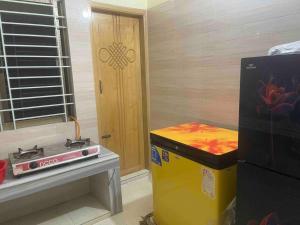 a kitchen with a stove and a refrigerator next to a door at Your home Away in Sylhet