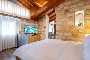 a bedroom with a white bed and a tv at Via Maria Boutique Suites In The Middle Of The city in Haifa