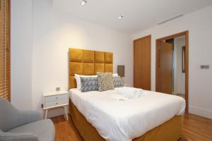 a bedroom with a large white bed and a chair at Imperial Piccadilly Apartments in London