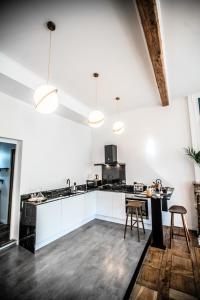 - une cuisine avec des placards blancs, une table et des chaises dans l'établissement Appartement entier Le 1er Balnéothérapie Romantique, à Bagnères-de-Bigorre