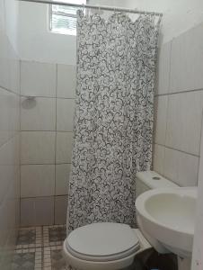 a bathroom with a toilet and a shower curtain at Chalé da Vovó in Soure