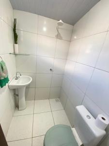 a white bathroom with a toilet and a sink at Lazer Hostel in Barreirinhas