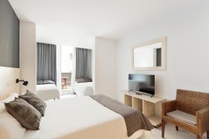 a bedroom with a bed and a chair and a television at Andreas Apartments in Tarragona