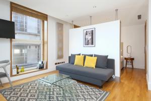 uma sala de estar com um sofá azul com almofadas amarelas em Imperial Piccadilly Apartments em Londres