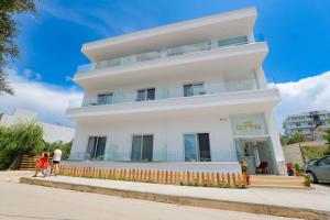 a white building with two people walking in front of it at Otto Hotel in Ksamil