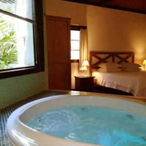 a bath tub in a room with a bedroom at Canto do Bosque - Chalé Sabiá com hidromassagem in Araras Petropolis