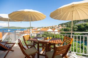 un balcón con mesa, sillas y sombrillas. en Apartments Karisima2 en Korčula
