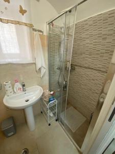 een badkamer met een glazen douche en een wastafel bij La casa sotto il castello! in Carovigno
