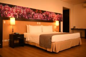 ein Schlafzimmer mit einem großen Bett und einem Gemälde an der Wand in der Unterkunft Mi Hotel Sandiego in Medellín