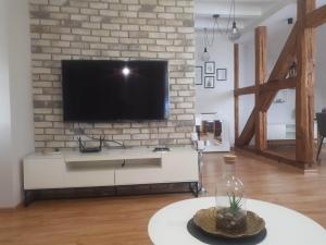 a living room with a tv on a brick wall at Apartament Ostoya 2 w centrum Ełku in Ełk