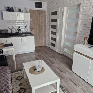 a kitchen and living room with white cabinets and a table at APARTAMENT - PORTA MARE - LEŚNE TARASY - 45B/2 in Dziwnówek