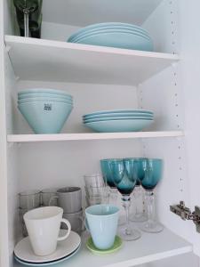 a shelf filled with plates and bowls and glasses at Studio Porin Karhu, home away home in Pori city center, free parking in Pori