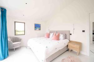 セント・アグネスにあるKarenza Luxury Cornish escapeの白いベッドルーム(ピンクの枕が付いた大型ベッド付)