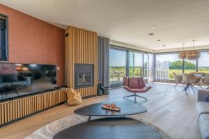 a living room with a fireplace and a tv at Natuurvilla 16 Weegeswaal in De Waal