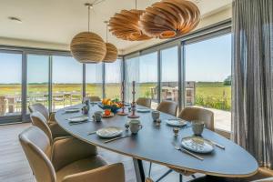 a dining room with a table and chairs and large windows at Natuurvilla 16 Weegeswaal in De Waal