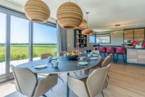 a dining room with a table and chairs and windows at Natuurvilla 16 Weegeswaal in De Waal