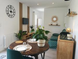 uma sala de estar com uma mesa e um sofá em Tiny House moderne et son jardin privé - 5mn Roanne 