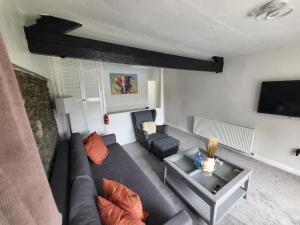 a living room with a couch and a tv at Courtyard Cottage in Cartmel