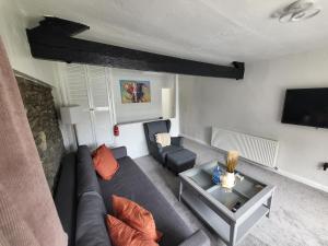ein Wohnzimmer mit Sofa und Fernseher in der Unterkunft Courtyard Cottage in Cartmel