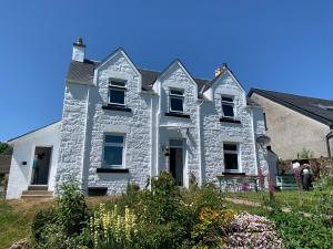 uma velha casa de pedra num quintal com flores em Burnbank BnB em Tobermory