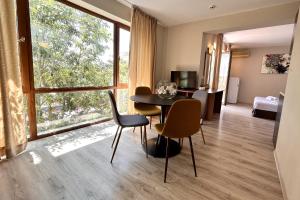 une salle à manger avec une table, des chaises et une grande fenêtre dans l'établissement Apart Hotel Primavera 2, à Primorsko