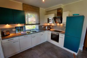a kitchen with white and blue cabinets and a sink at Villa Anima in Göhren-Lebbin +12 photos