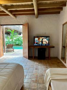 a bedroom with a bed and a flat screen tv at Villa Sagui Trancoso in Trancoso