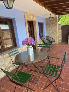 una mesa con sillas y un jarrón de flores en el patio en Villa Paraes, en Nava