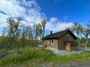 uma cabana de madeira no meio de um campo em Olderfjord Lodge em Russenes