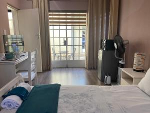 ロードポートにあるSafari Deluxe Rooms - elegant rooms with access to beautiful garden & poolのベッドと机と窓のある寝室