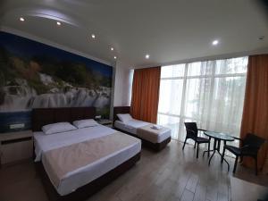 a hotel room with two beds and a table and chairs at Hotel Royal Palace in Batumi